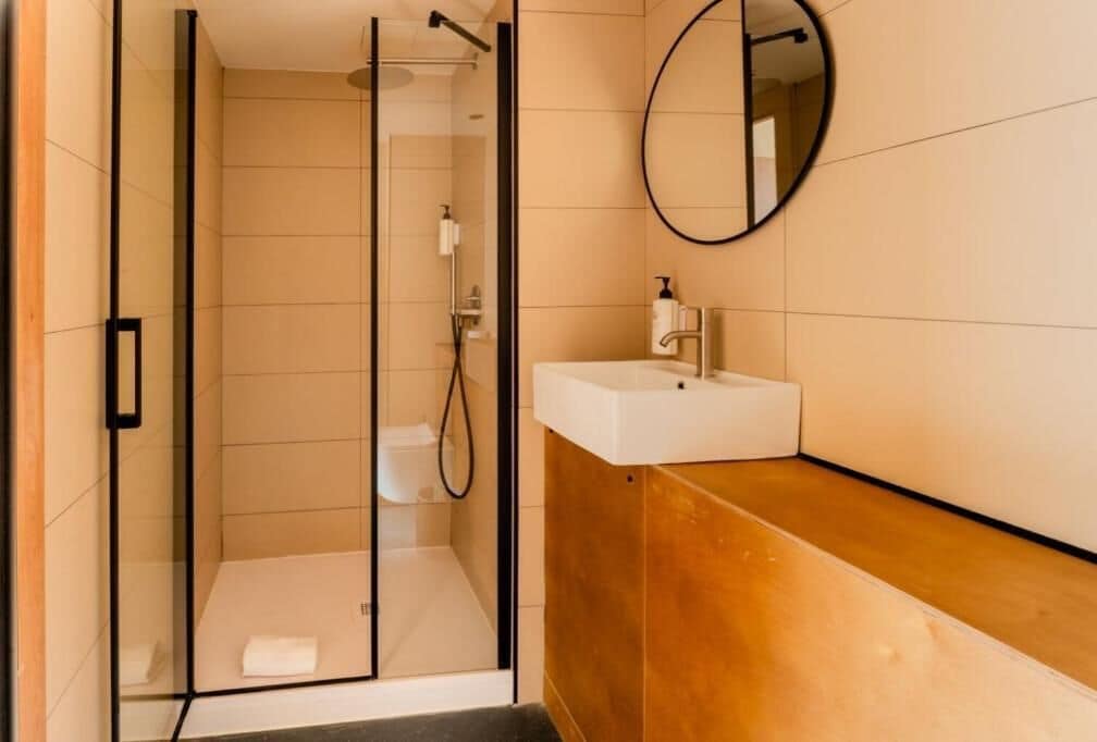 A modern bathroom with a glass shower enclosure, a white sink, and a wooden vanity.
