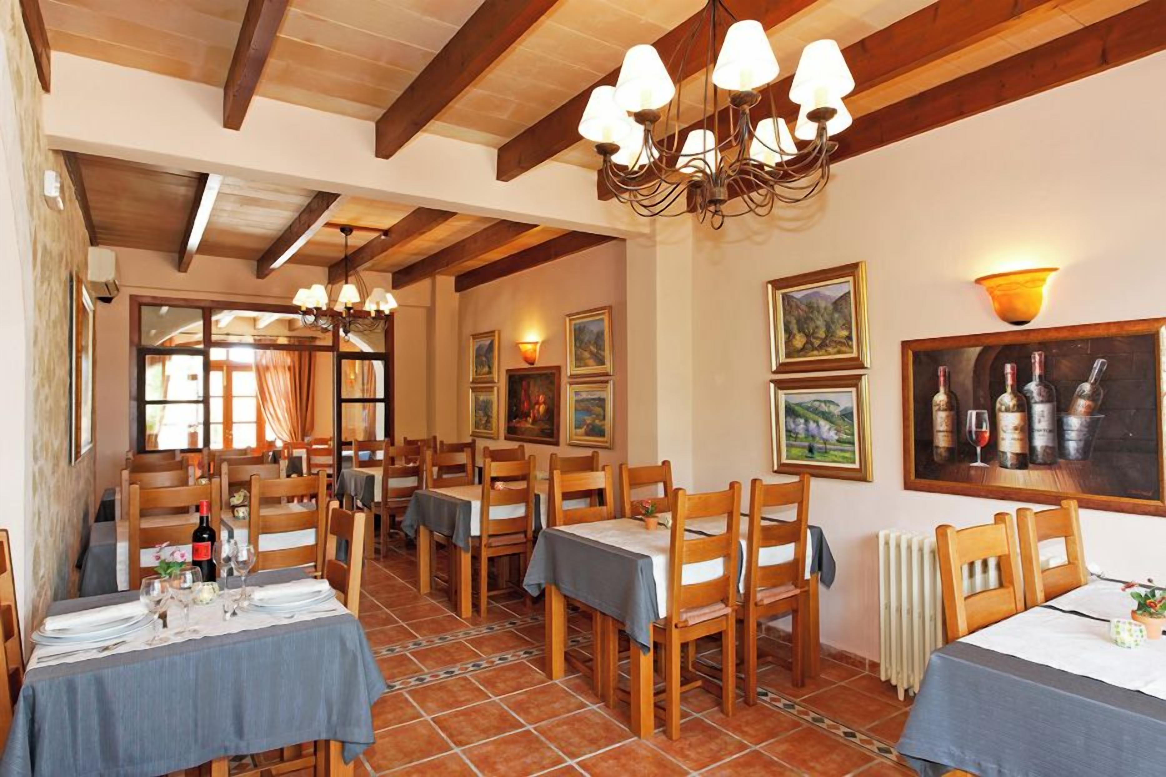 A dining area with wooden tables and chairs, a chandelier, and artwork on the walls.
