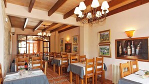 A dining area with wooden tables and chairs, a chandelier, and artwork on the walls. - Son Marge Sl.l (Ses Salines)