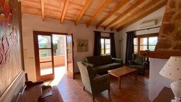 A spacious living room with a wooden ceiling, a sofa, a coffee table, and a lamp.