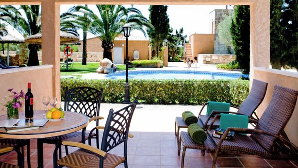 A covered outdoor area with a pool, lounge chairs, and a table with drinks and fruits. - Son Marge Sl.l (Ses Salines)
