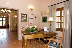A dining area with a wooden table, chairs, a flower vase, and a wall-mounted lamp. - Son Marge Sl.l (Ses Salines)