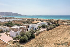 A coastal village with white buildings, a beach, and a hilly backdrop. - Plaka II (Naxos)