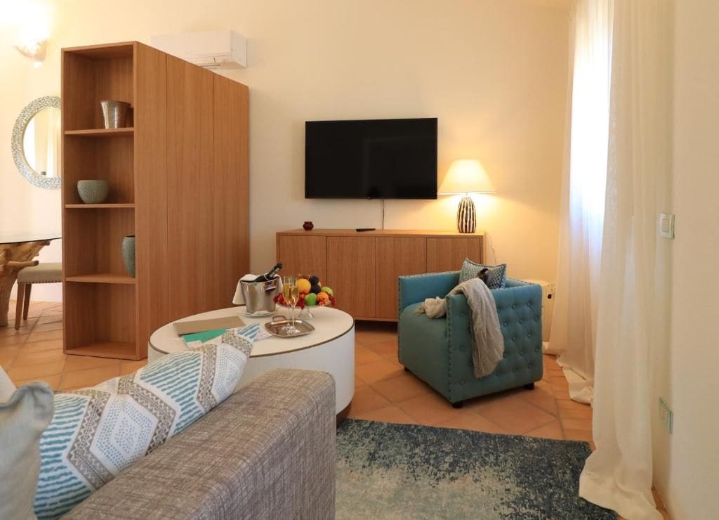 A living room with a wooden cabinet, a blue sofa, a white coffee table, and a flat-screen TV.