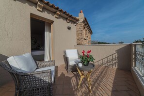A balcony with wicker furniture, a potted plant, and a view of the surrounding area. - Hotel Borgo Smeraldo (Olbia)