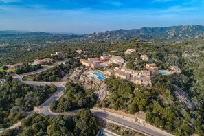 Un pueblo costero con edificios de piedra, caminos sinuosos y una amplia zona de piscina.