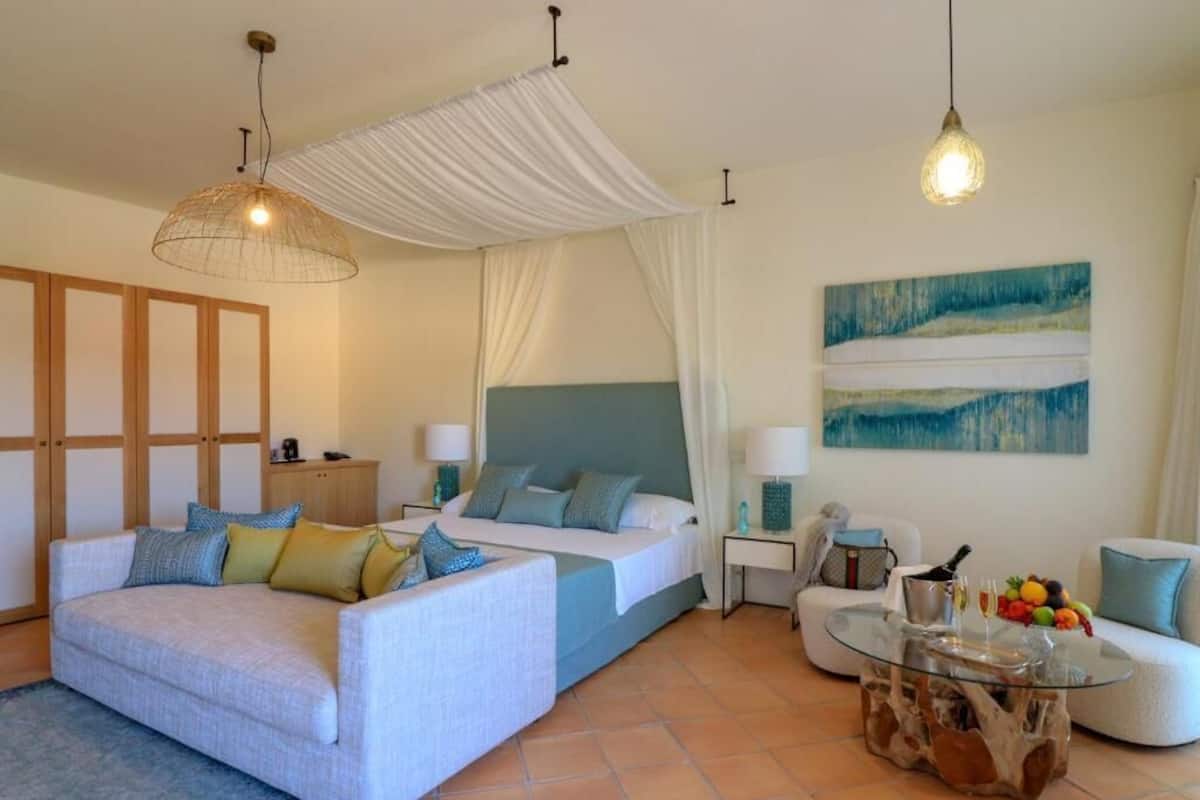 Une chambre d’hôtel moderne avec un lit, un canapé et une table basse en verre.