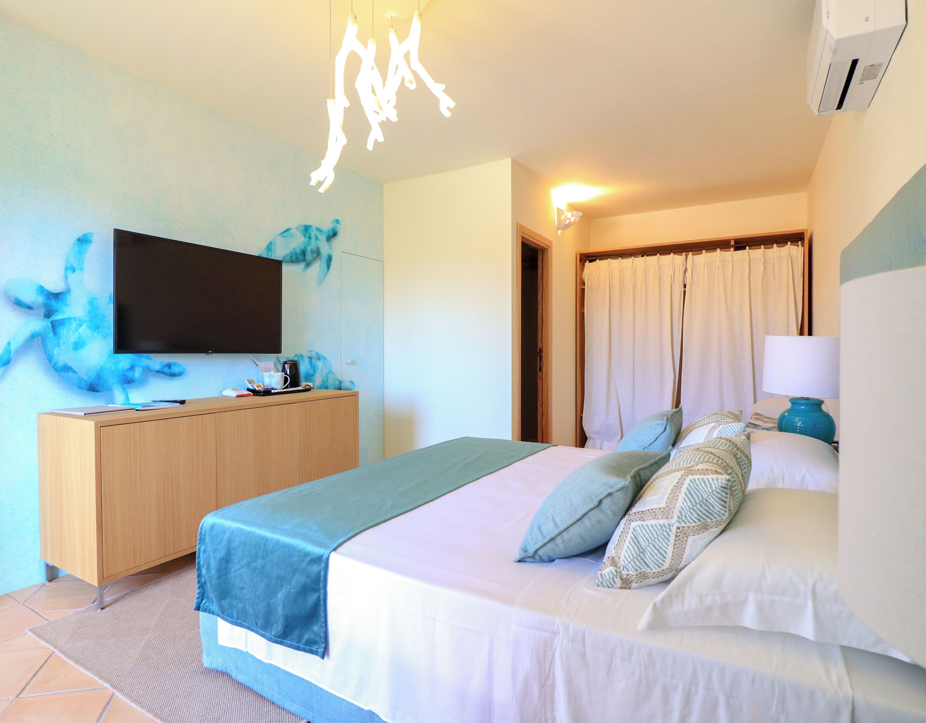 A hotel room with a bed, a TV, a wooden dresser, and a bathroom door.