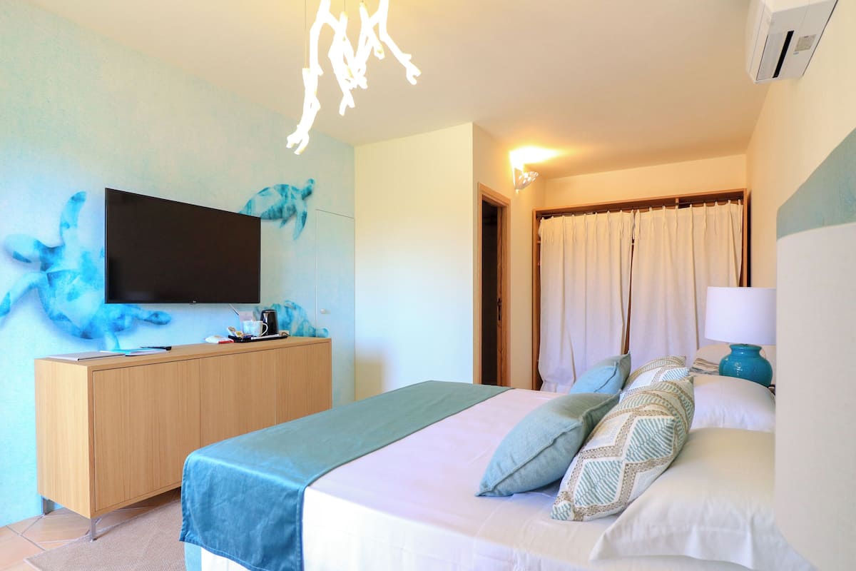 Une chambre d’hôtel avec un lit, une télévision, une commode en bois et une porte de salle de bain.