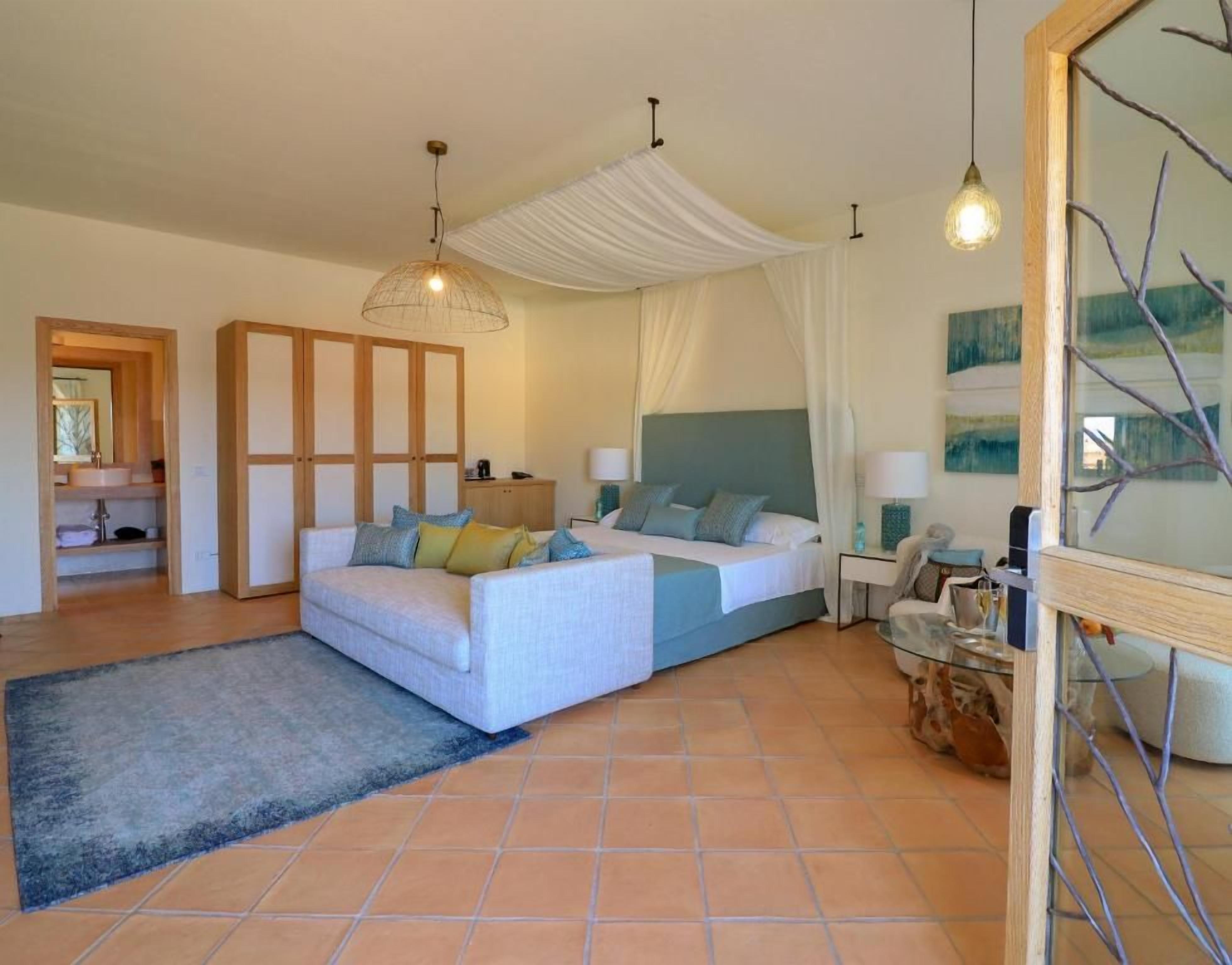 Een slaapkamer met een bed, nachtkastjes, een spiegel en een raam met gordijnen.
