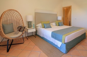 A bedroom with a bed, a chair, a nightstand, and a door. - Hotel Borgo Smeraldo (Olbia)