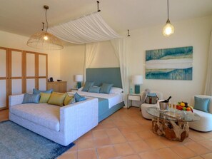 A modern hotel room with a bed, sofa, and a glass coffee table. - Hotel Borgo Smeraldo (Olbia)
