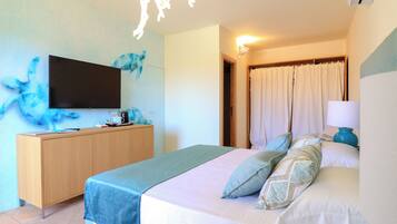 A hotel room with a bed, a TV, a wooden dresser, and a bathroom door.