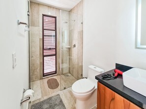 Une salle de bain moderne avec une douche à parois de verre, des toilettes et un lavabo doté d’un plan de travail noir.