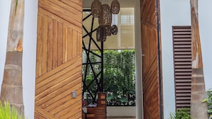 A modern entrance with wooden paneling, a hanging light fixture, and a staircase leading to a covered area with plants. - Luxury Boutique Hotel Villas Jardin Caracol Tulum (Tulum)