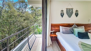 A bedroom with a balcony, wooden headboard, and a view of trees. - Luxury Boutique Hotel Villas Jardin Caracol Tulum (Tulum)