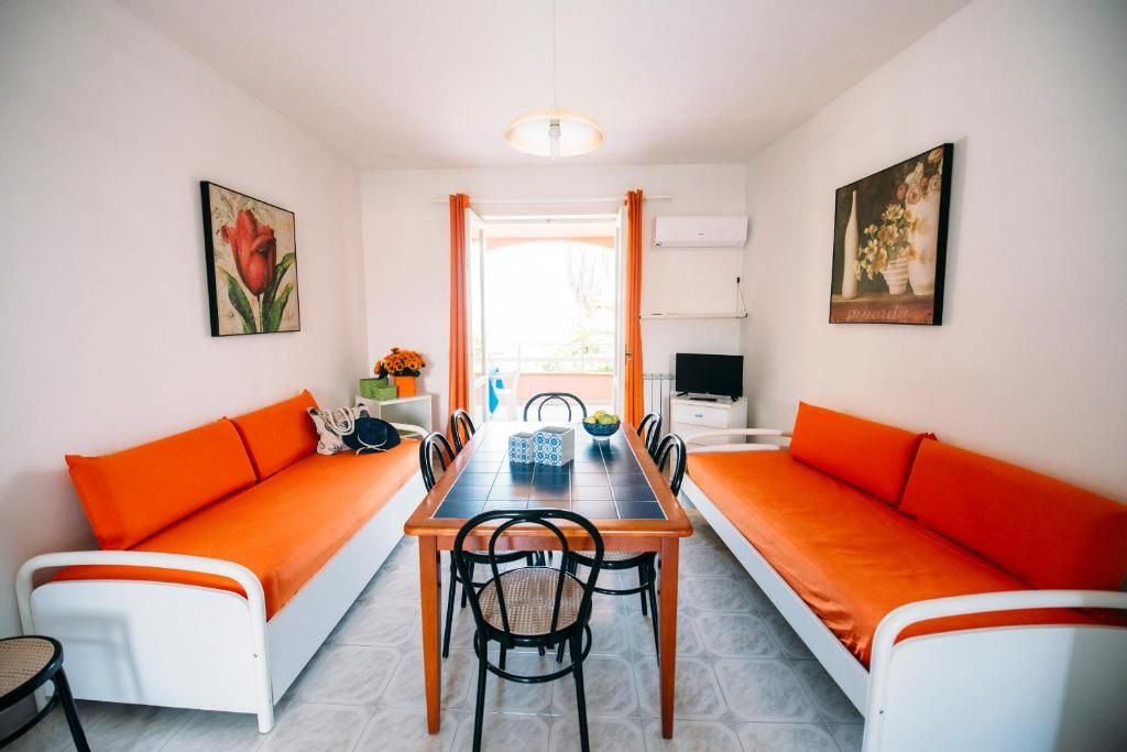 Ein Essbereich mit einem langen Tisch, orangenen Kissen und Stühlen.