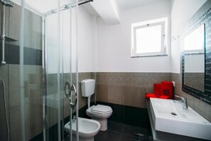 A modern bathroom with a glass shower enclosure, a toilet, bidet, and a sink. - Porto Rosa (Furnari)