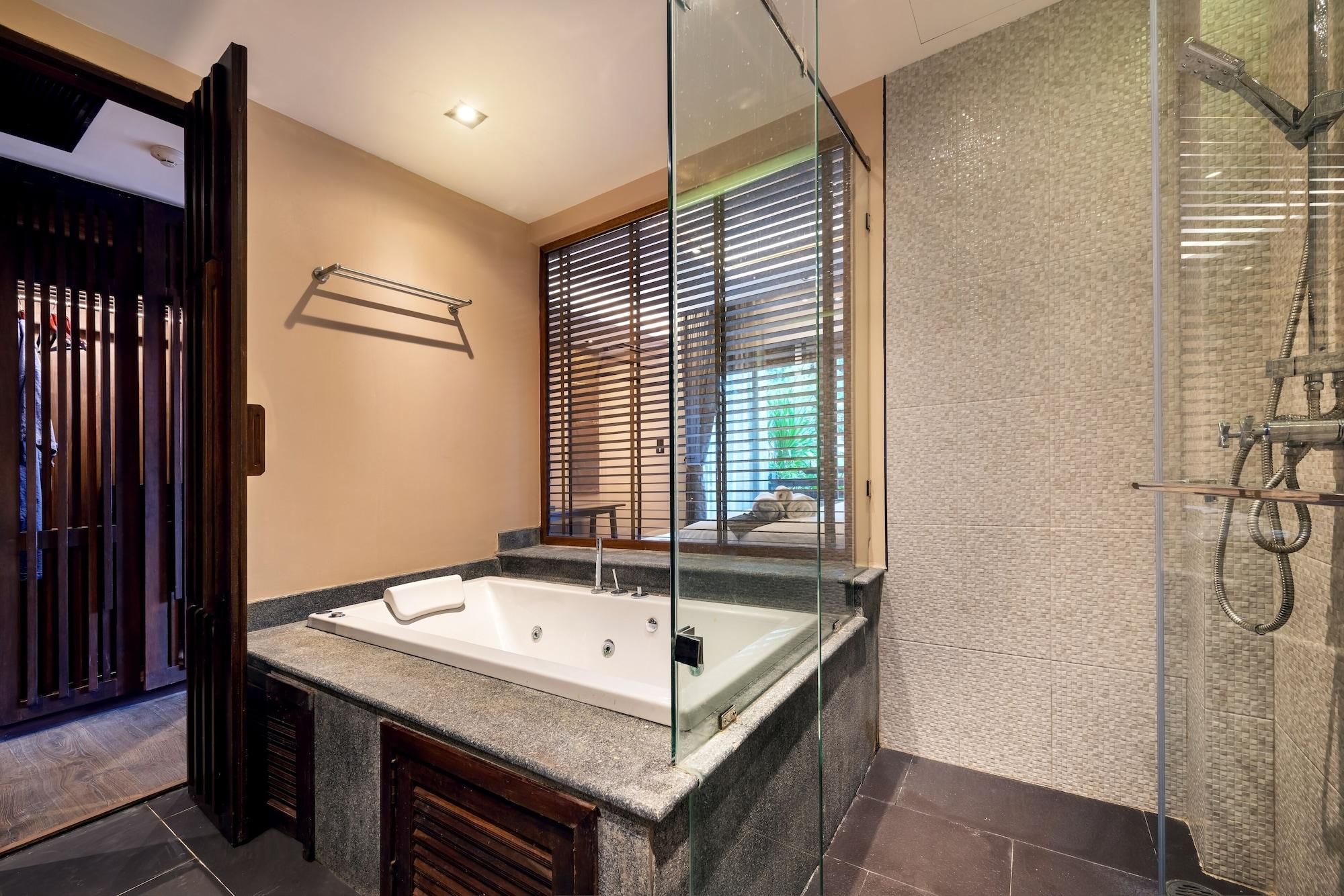 Un baño moderno con una bañera independiente, cabina de ducha con mampara de vidrio y un amplio ventanal con persianas.