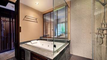 Un baño moderno con una bañera independiente, cabina de ducha con mampara de vidrio y un amplio ventanal con persianas.