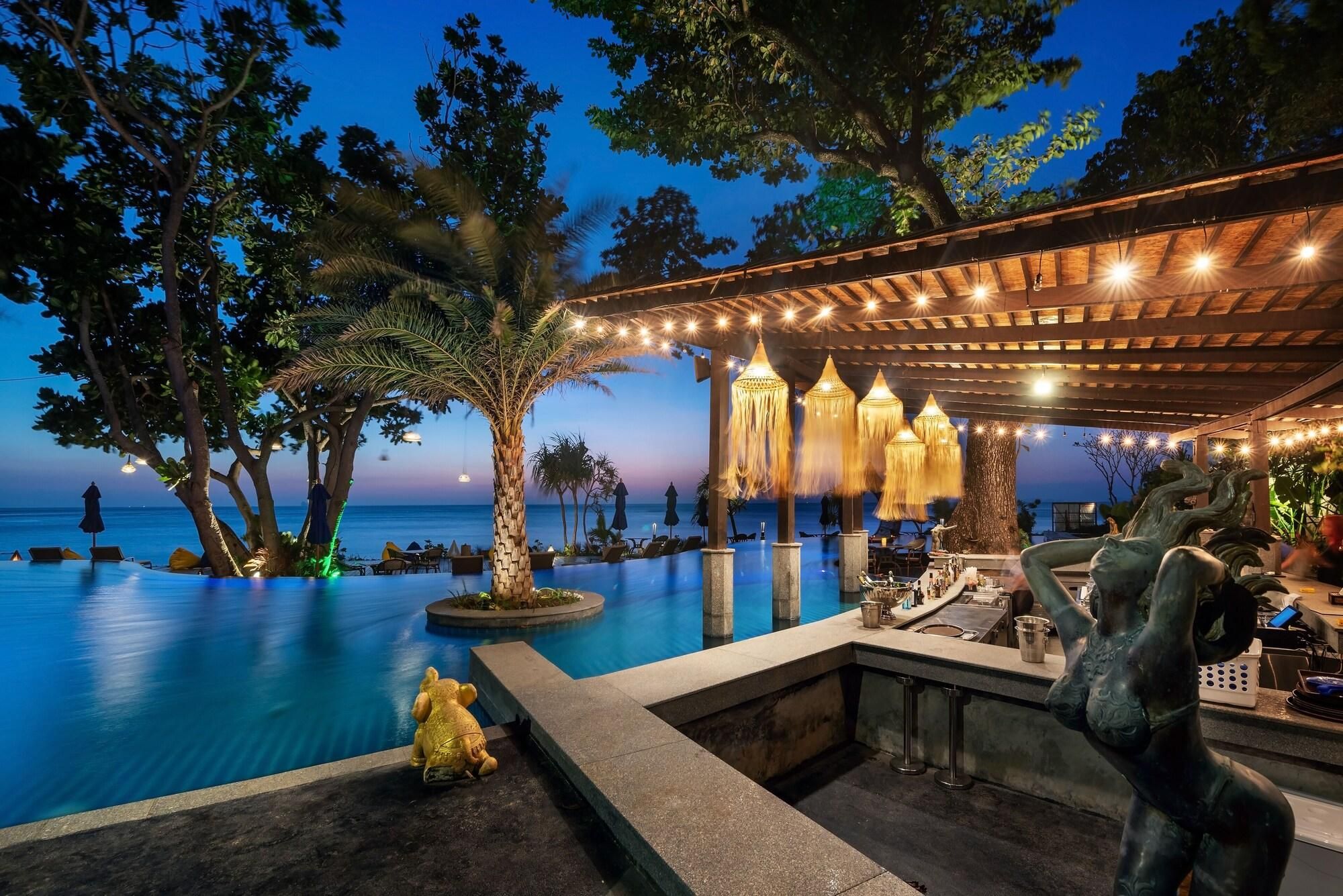 A poolside bar area with a view of the ocean, surrounded by trees and string lights.