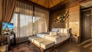 Un dormitorio amplio con una cama grande, una mesita de noche, un televisor y vistas a la playa.