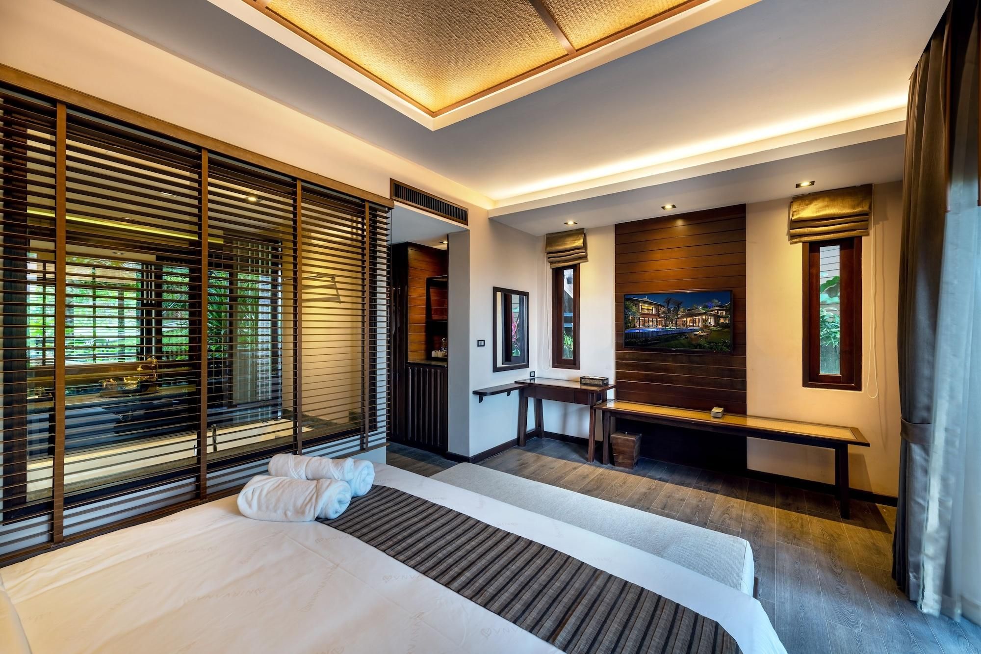 A modern hotel room with a large bed, a desk, and a TV.