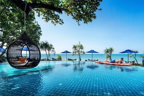 A pool area with a hanging chair, lounge chairs, and umbrellas. - Nirvana Beach Resort (Ko Lanta)