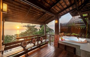 A wooden deck with a bench and a spa area with a bathtub and a small table.