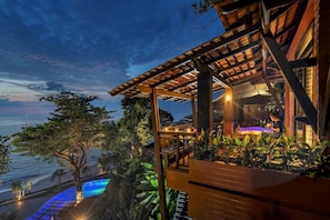 A wooden structure with a pool and a view of the ocean at dusk.