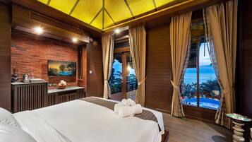 Habitación de hotel con una cama grande, un escritorio y un televisor de pantalla plana, y vistas al mar.