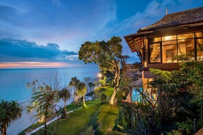 A modern house with a large glass window overlooking a beach and ocean. - Nirvana Beach Resort (Ko Lanta)