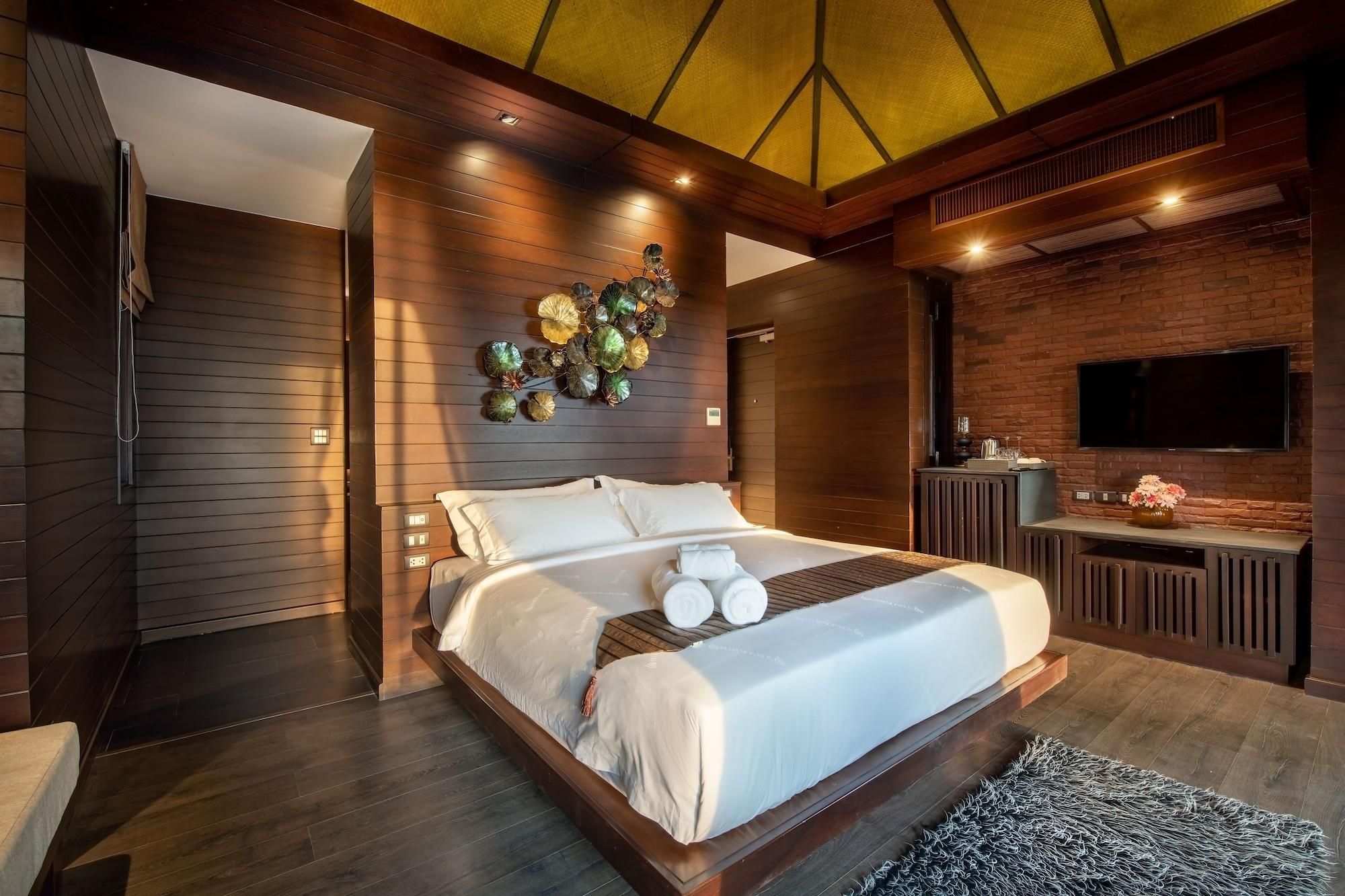 Quarto moderno com uma cama grande, TV na parede e um objeto decorativo na parede.