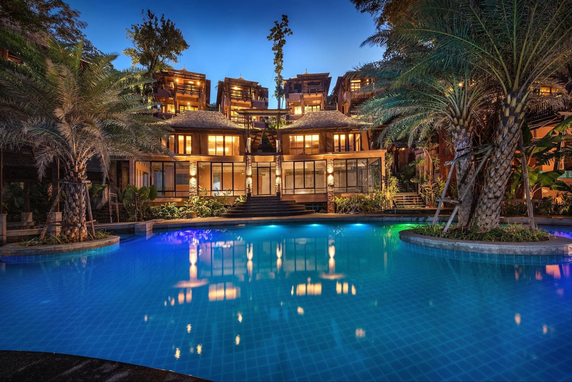 Un resort lujoso con una amplia piscina, varias villas para huéspedes y exuberante vegetación tropical.