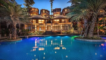 Un resort lujoso con una amplia piscina, varias villas para huéspedes y exuberante vegetación tropical.