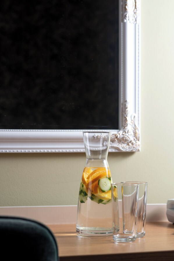 A pitcher with fruit slices and two clear glasses on a table.