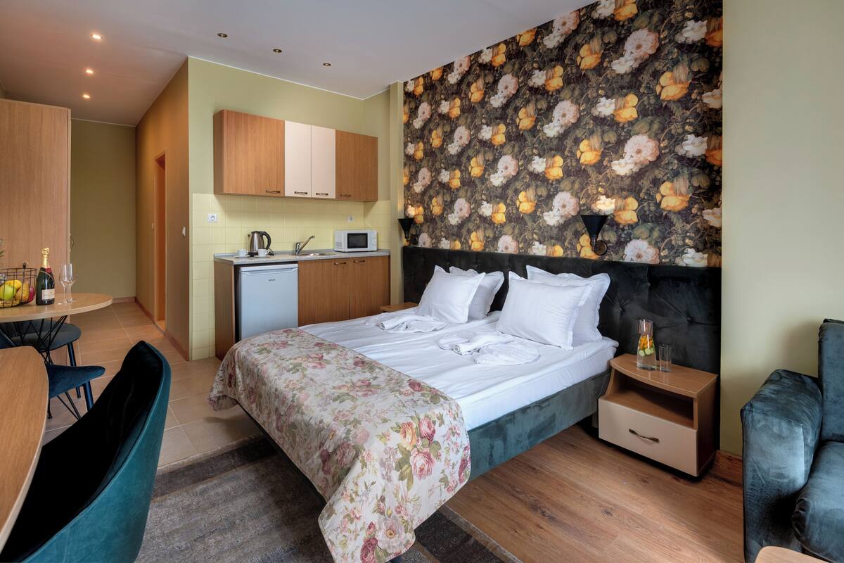 Une chambre d’hôtel équipée d’un lit, d’un bureau, d’une chaise, d’un four à micro-ondes et d’un petit coin cuisine.
