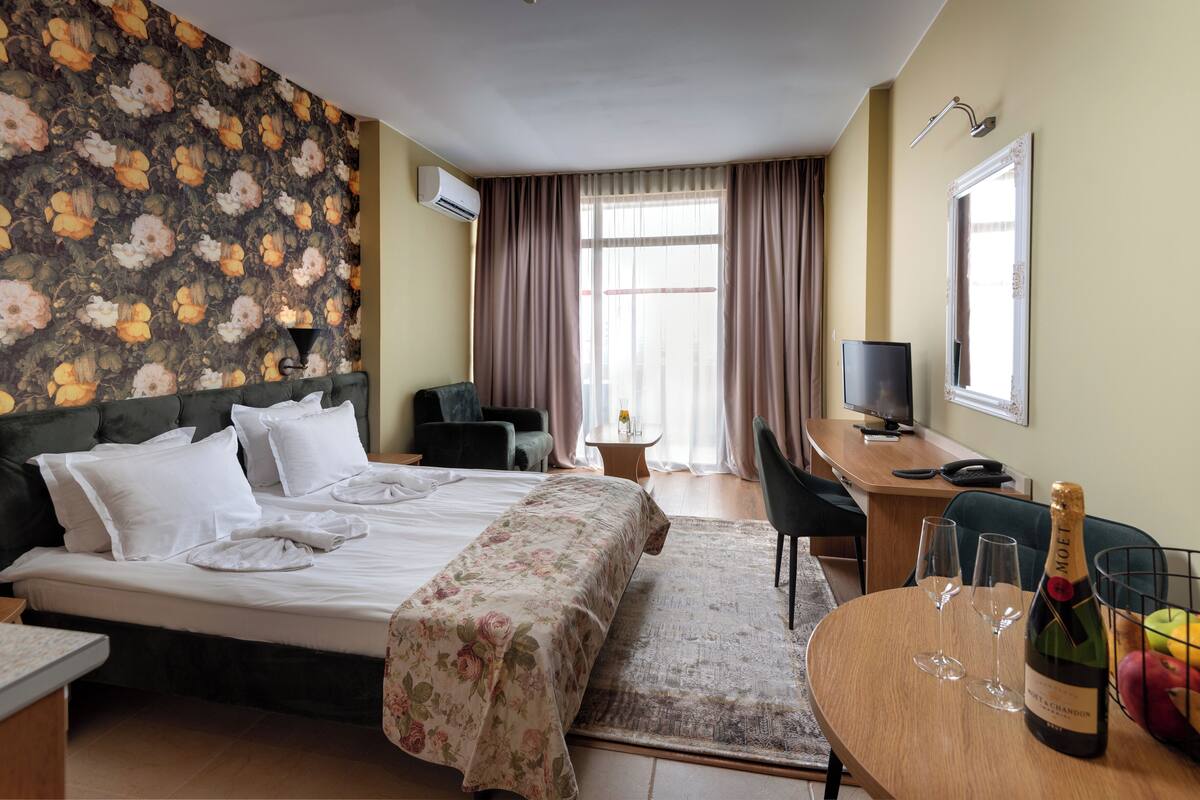 Une chambre d’hôtel équipée d’un lit, d’un bureau, d’une chaise, d’une télévision et d’une bouteille de champagne.