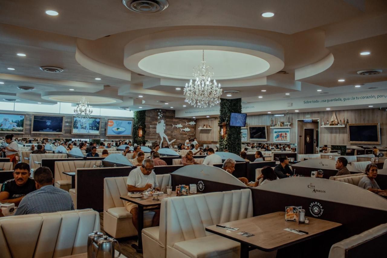 A spacious restaurant with multiple dining areas, including booths and tables, and a central decorative wall with artwork.