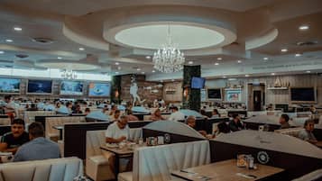 A spacious restaurant with multiple dining areas, including booths and tables, and a central decorative wall with artwork.