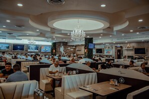A spacious restaurant with multiple dining areas, including booths and tables, and a central decorative wall with artwork. - Sky Inn Hotel (Cancun)