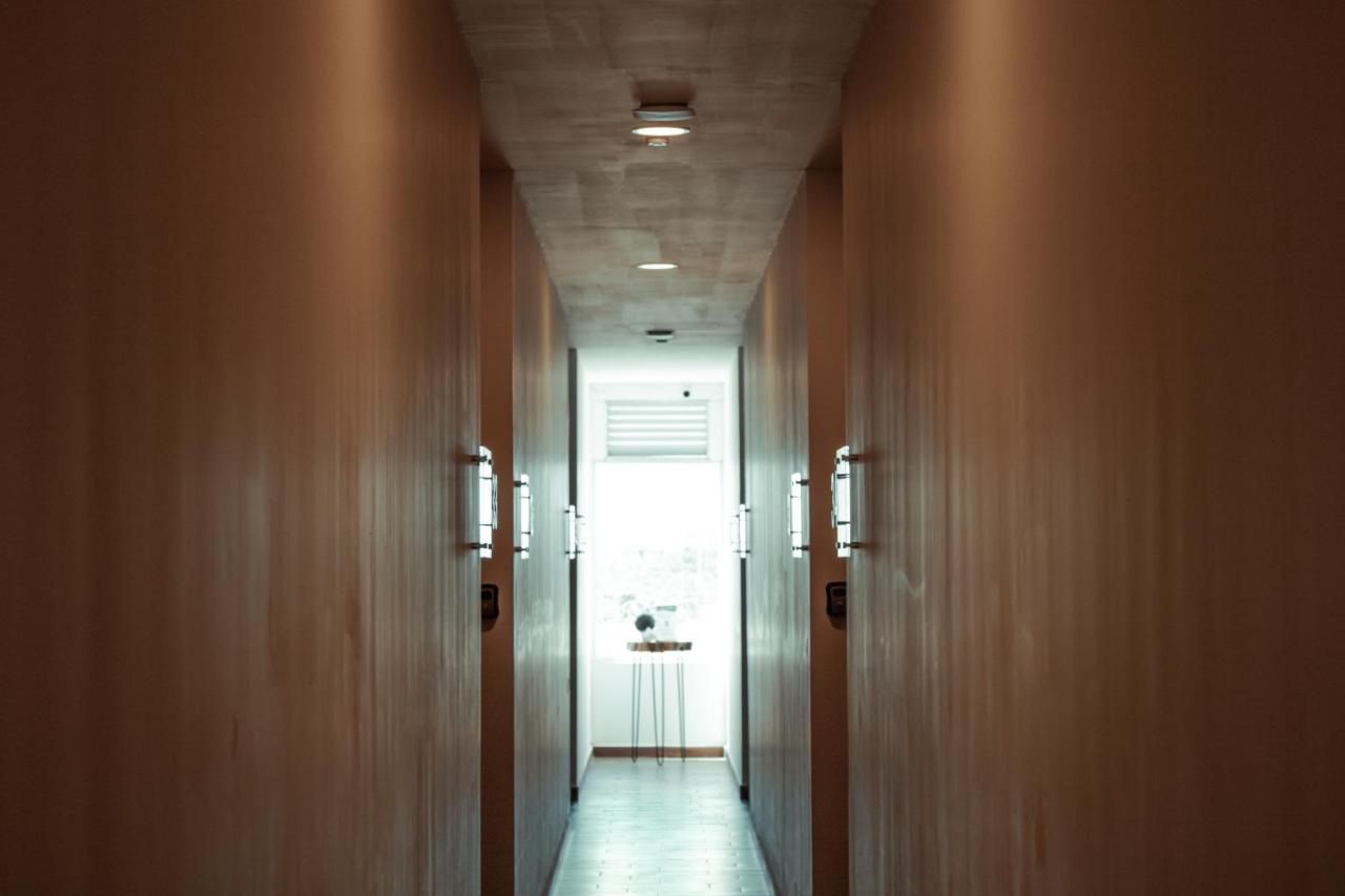 A hallway with wooden walls and a light-colored floor, leading to a door with a window.