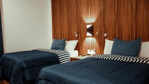 A hotel room with two beds, wooden headboard, and bedside tables with lamps. - Sky Inn Hotel (Cancun)