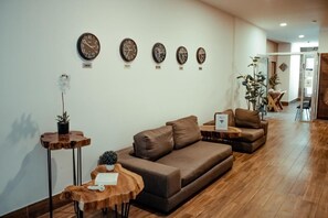 Un salon moderne avec un canapé marron, une table basse en bois et des horloges fixées au mur.