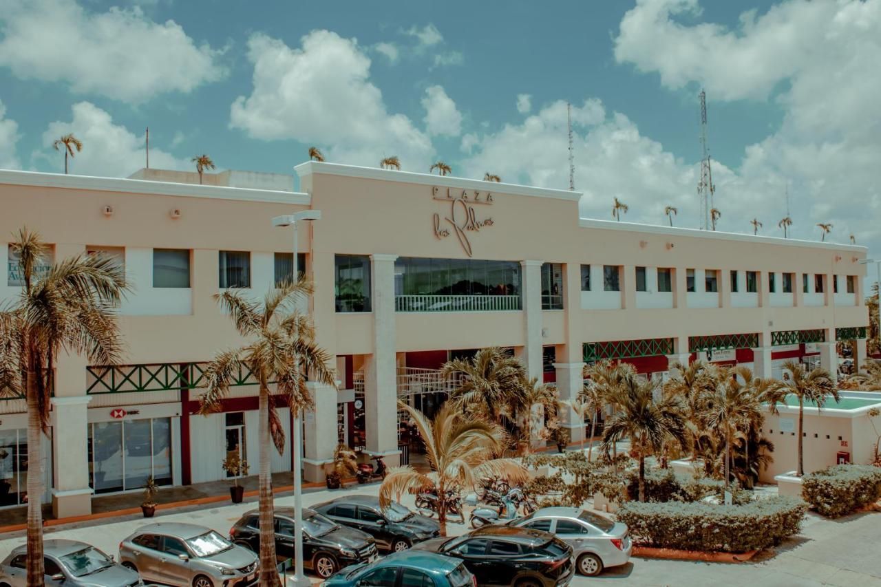 A hotel with a central atrium, palm trees, and a parking lot.