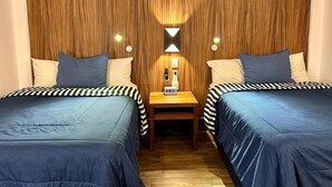A room with two beds, each with striped bedding, a nightstand with a clock, and a wall-mounted air conditioner. - Sky Inn Hotel (Cancun)