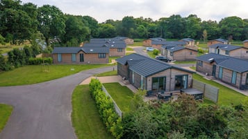 A residential area with multiple houses featuring modern architecture, a central driveway, and surrounding greenery.
