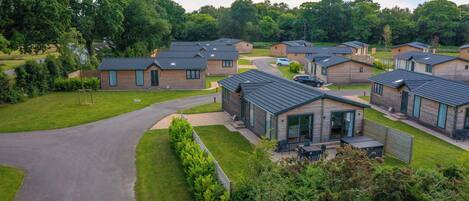 A residential area with multiple houses featuring modern architecture, a central driveway, and surrounding greenery.