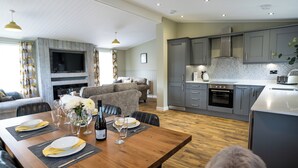 A modern kitchen with grey cabinets, a built-in oven, and a microwave. - Chestnut Meadow Country Park (Bexhill-on-Sea)