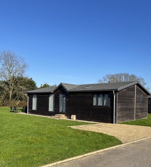 A modern two-story wooden house with a gravel driveway and a grassy lawn. - Chestnut Meadow Country Park (Bexhill-on-Sea)